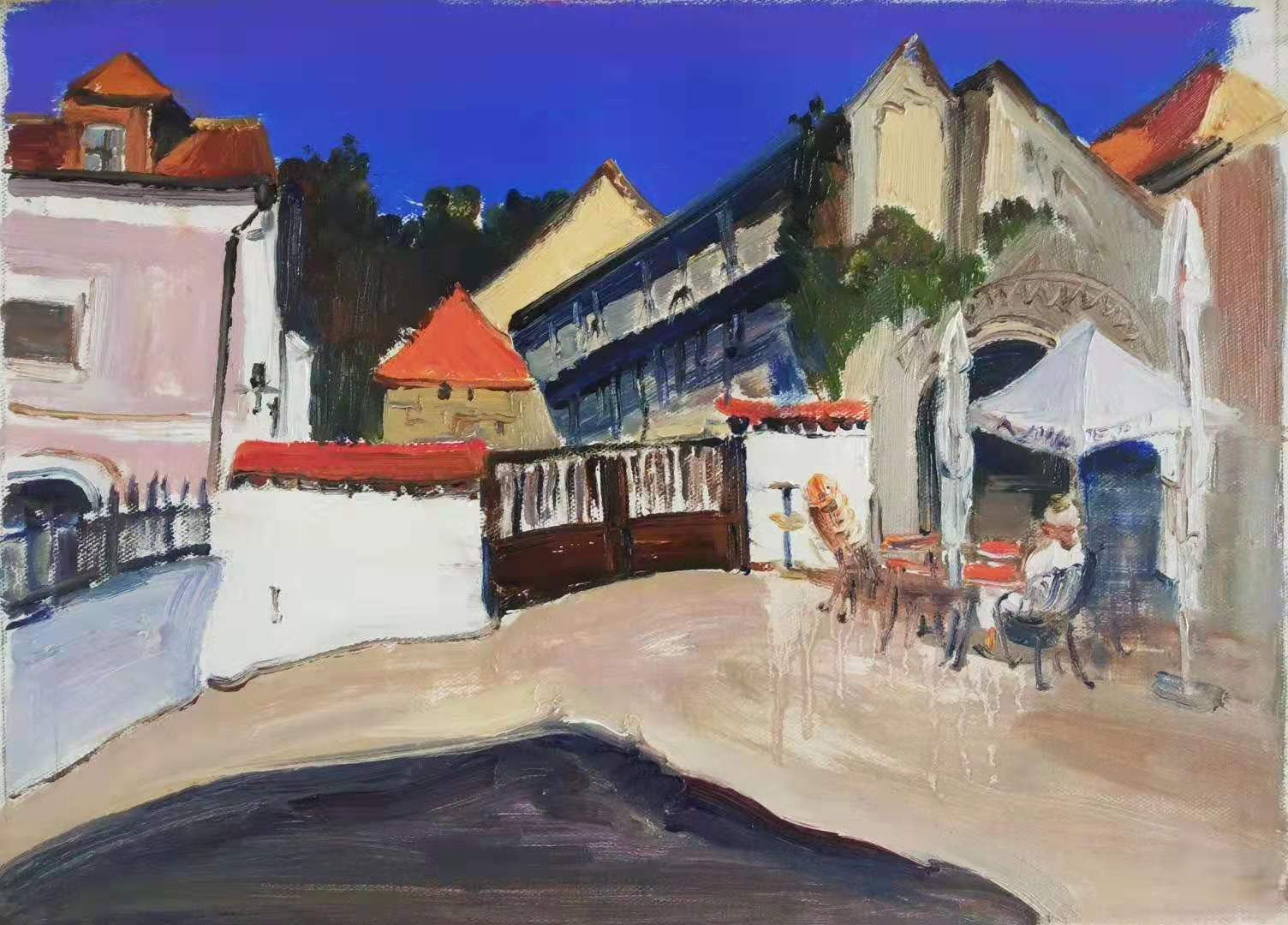 townscape scene with low buildings in background and patio furniture with white umbrella bright blue sky