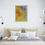 Thumbnail: painting on light gray wall above large bed with multiple white pillows tan bed sheets blanket