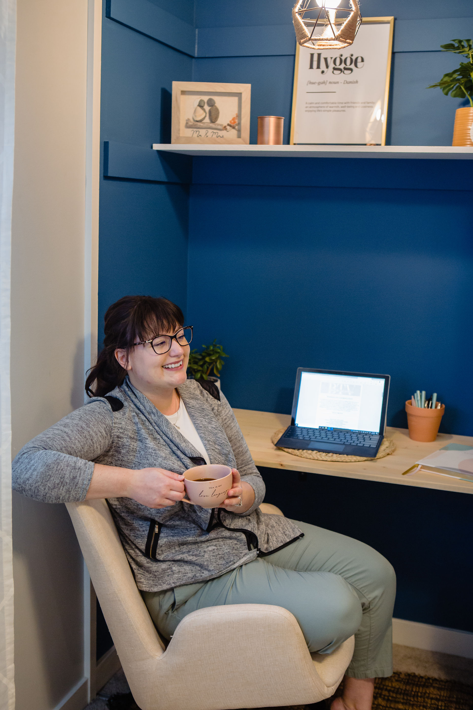 Kamloops Wedding Planner from behind the veil weddings smiles with a cup of coffee while sitting at their desk at their home office. il