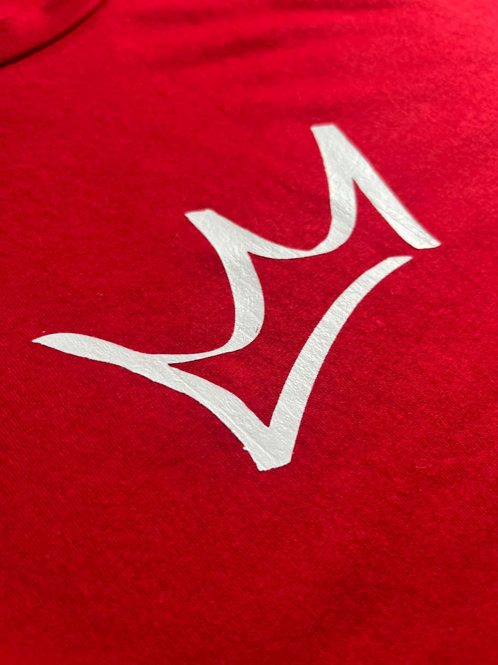 Thumbnail: Close up of white crown on red rosaic shirt
