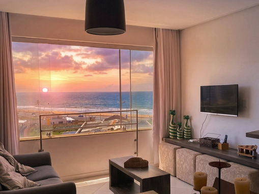 Close-up da sala com janela grande com vista para o mar e orla de Salvador pra aluguel por temporada