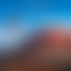 Ein rot schimmernder Vulkan in der Abendsonne, sanfte Wolken am Himmel, Schattenspiel auf der kargen Mondlandschaft, im Hintergrund das Meer, pures Lanzarote-Feeling (KI-generiert) und im Vordergrund die Schweizer Flagge im Passatwind wehend, Blogbild zum Schweizer Nationalfeiertag in der Ferne auf den kanarischen Inseln, Wortfeger Atelier