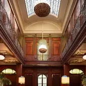 Eine hohe Hotelhalle mit Galerie und viel Holz, Oberlicht und im Stil der 1920er-Jahre, wie sie vielleicht im Buch "Ein Gentleman in Moskau" von Amor Towles hätte aussehen können, Buchrezension und Reflexionen, Blog Wortfeger Atelier