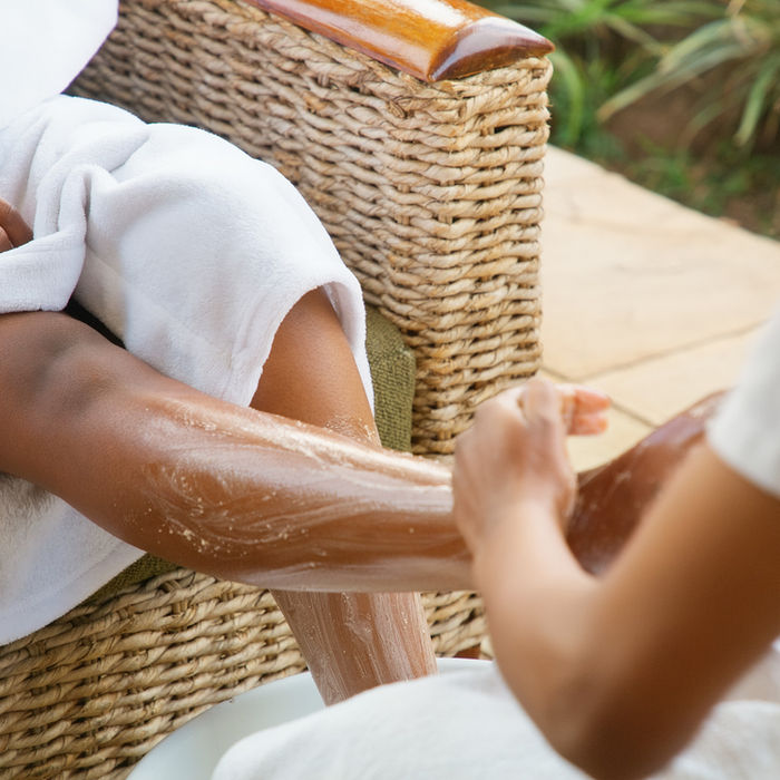 A person sitting getting their feet and legs scrubbed by another person