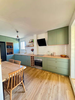 Cuisine contemporaine avec poignées dorées, hotte design, crédence blanche et meubles vert eucalyptus – réalisation artisanale locale.