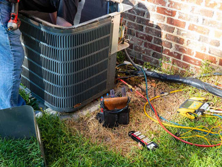 HVAC technician working on an outdoor air conditioning unit; AC system needs repair