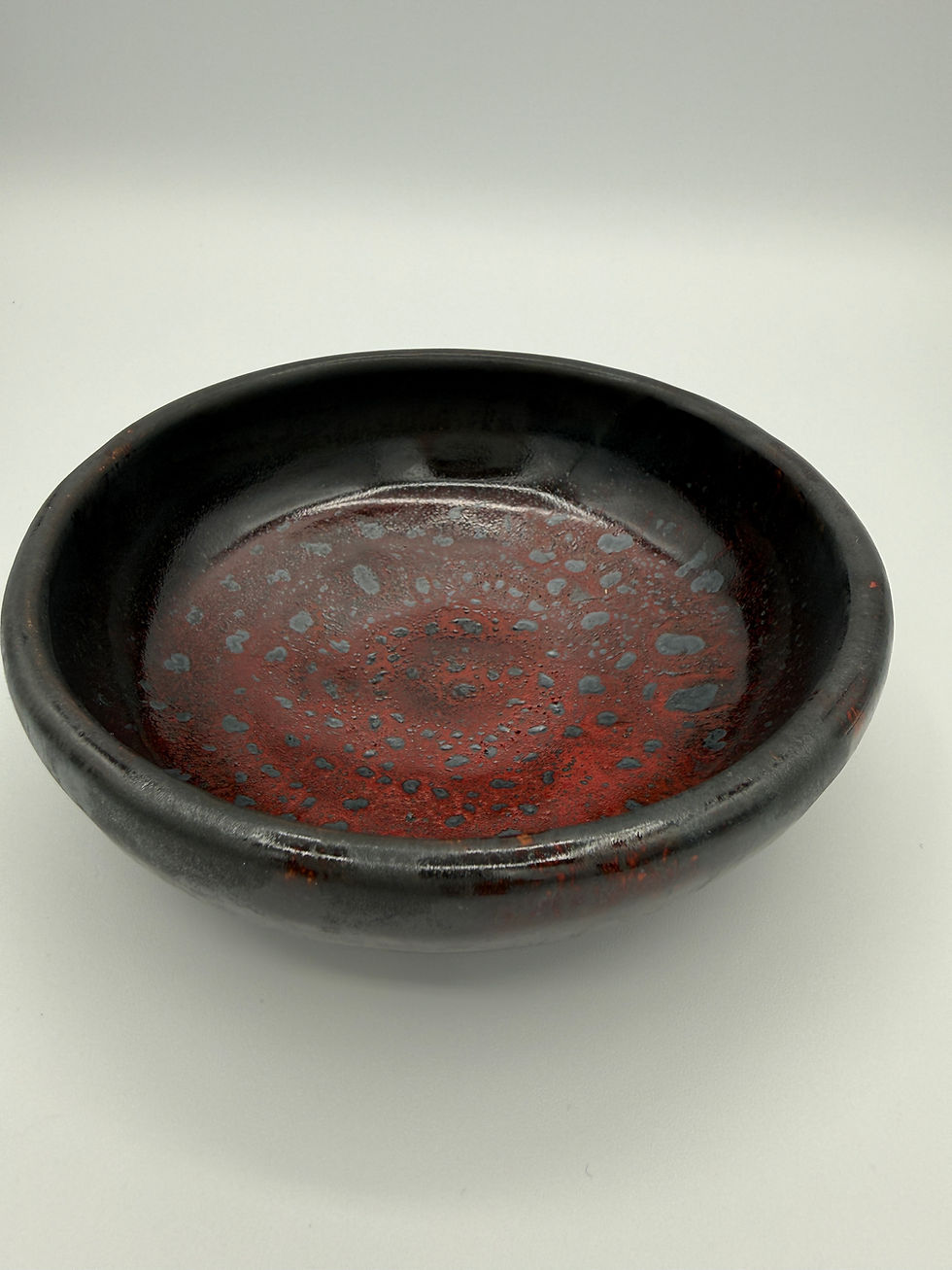 small dish in black glaze with spackled red glaze
