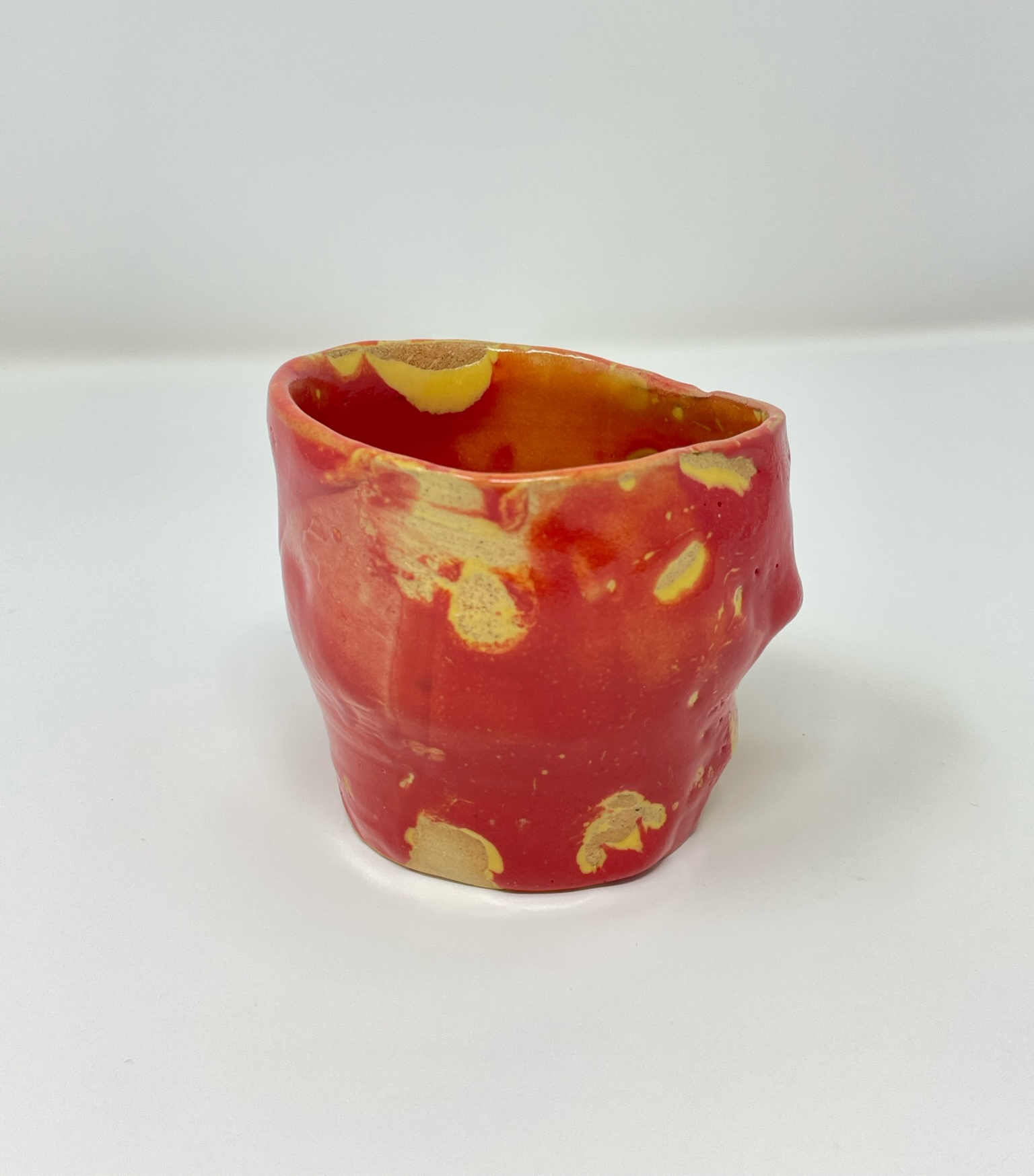 Knobby oval shaped thin teacup without handles in red and natural glaze
