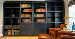 A massive custom floor-to-ceiling bookshelf unit painted in a navy color.