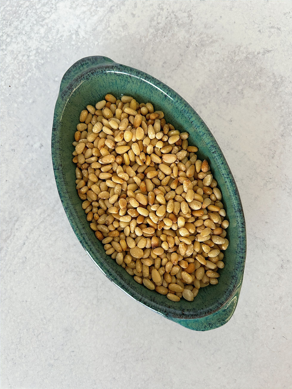 Pine nuts, also known as pignoli or pignolia nuts, are the edible seeds of a certain species of pine trees. Commonly called "nuts" they are botanically seeds. They have a delicate, buttery flavor and a soft texture. Toasting them enhances their flavor.