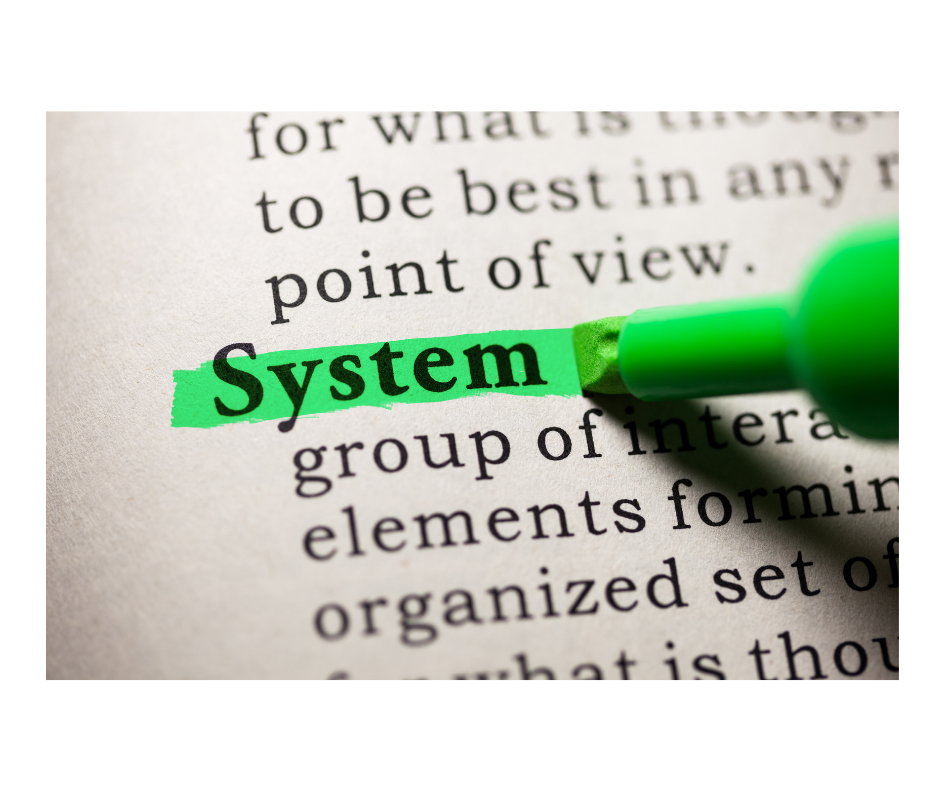 The word "System" highlighted in green in a dictionary, symbolizing the focus on understanding and transforming restorative systems in education.