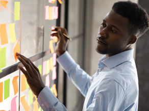 A teacher analyzes data using a wall covered in sticky notes, visually organizing key insights to track student progress and classroom trends. This method, like digital dashboards, helps educators make informed, real-time decisions about student learning.