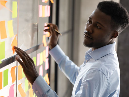 A teacher analyzes data using a wall covered in sticky notes, visually organizing key insights to track student progress and classroom trends. This method, like digital dashboards, helps educators make informed, real-time decisions about student learning.