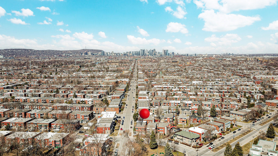 Vue aérienne d'une rue bordée de maisons, avec un point rouge. Location Prive.