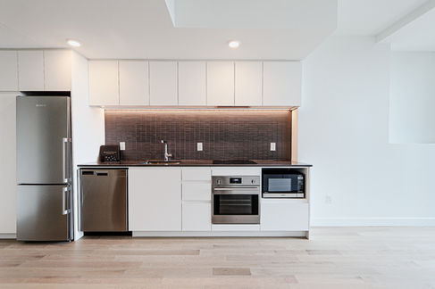 Cuisine moderne avec des appareils électroménagers, plan de travail et armoires blancs Location Prive