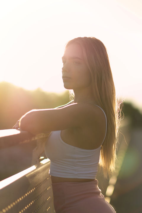 Portraitfoto einer jungen blonden Frau an einem Brückengeländer bei Augsburg. Die Abensonne verleiht dem Bild eine besondere Stimmung.