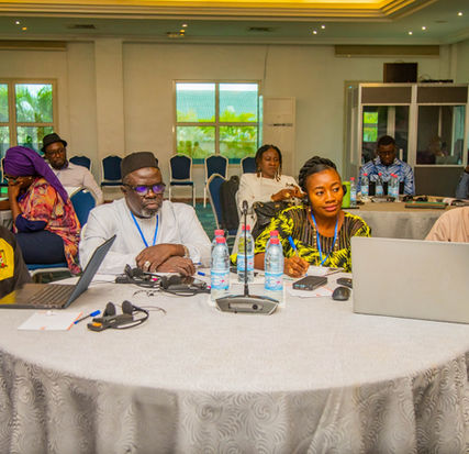 Four participants of the CORAF-organized regional workshop on the technical validation and budgeting of the PRAIC-AO sitting around a table with their laptops.