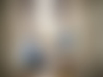 Kneeling mother putting socks on a toddler sitting on the edge of the bed.