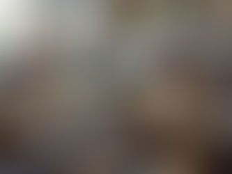 Two women work with leather while sitting at the sewing machines of a small shoe shop.