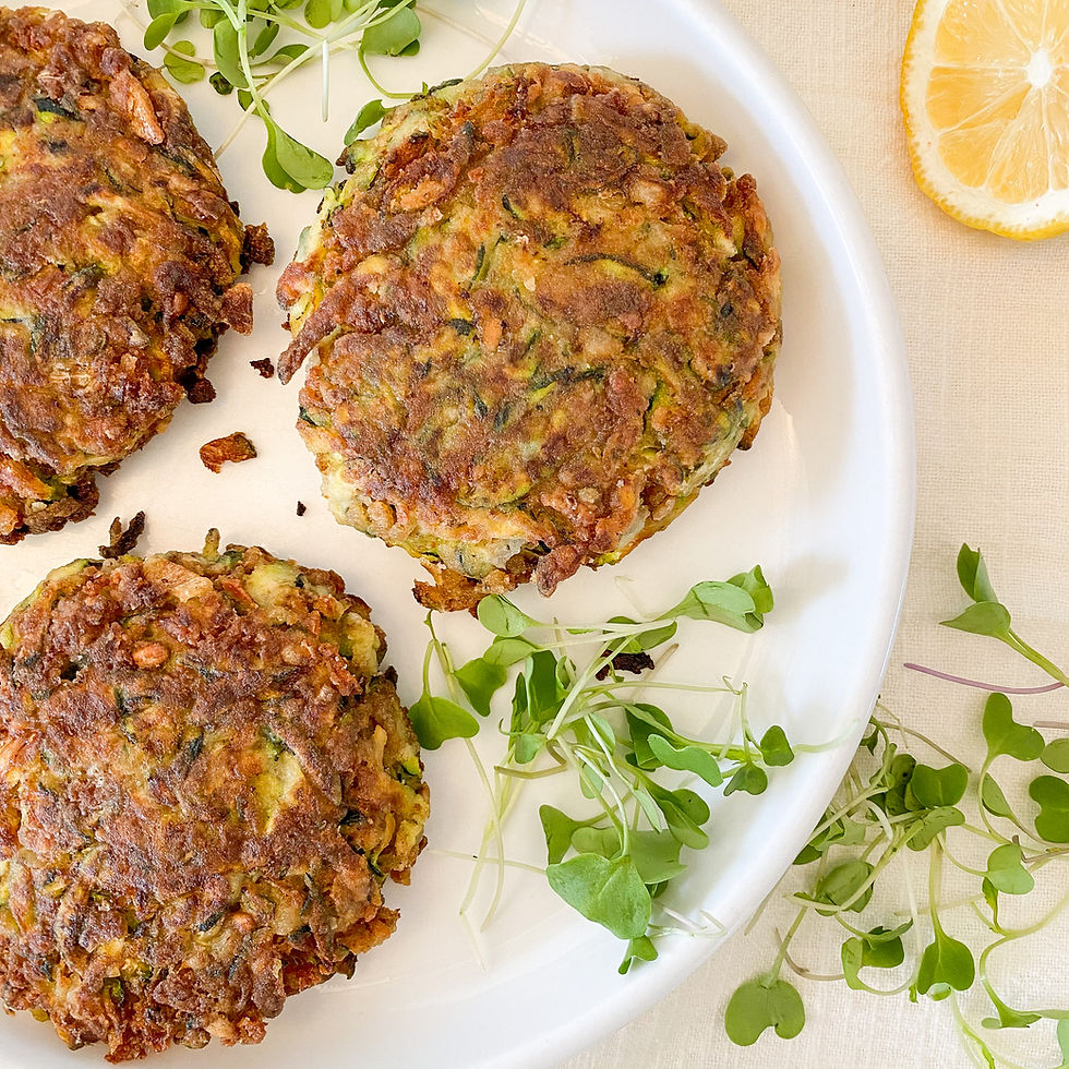 Zucchini crab cakes on a white plate with a side of micro greens and lemon