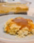 A plate with baked mashed potatoes topped with brown gravy. In the background, a glass dish with more casserole. Warm, homemade feel.