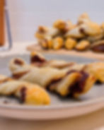 Twisted pastries with chocolate filling on a gray plate; more pastries are on a wooden board in the background. Light, cozy kitchen setting.