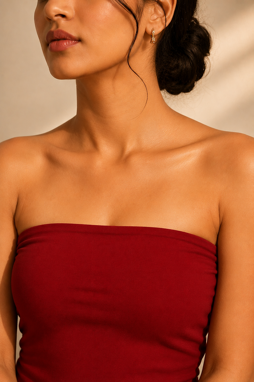 Woman wearing a deep red strapless top with her dark hair in an elegant low bun.