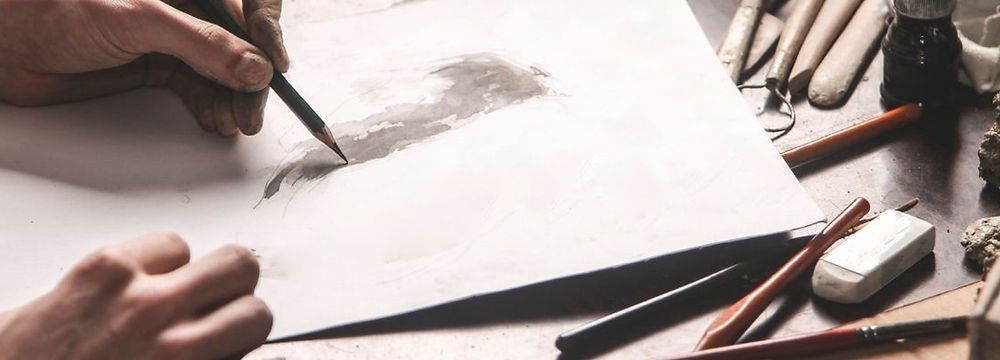 Person drawing on a piece of paper on a drafting table.