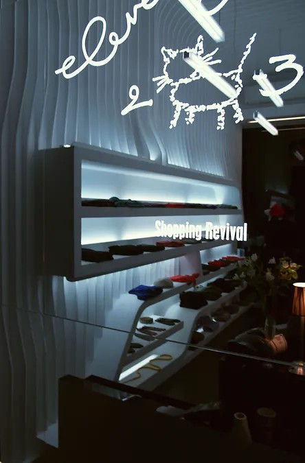Retail store interior with sculpted white shelving, black feature wall, and glossy black counter by 9901 Architects.