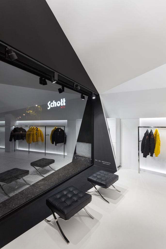 Contemporary retail store design with sculptural black staircase, geometric white interior, and minimalist clothing showroom layout by 99 01 architects.