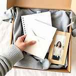 show a hand opening a subscription box in neutral light gray, creamy, dark blue colors.jpg