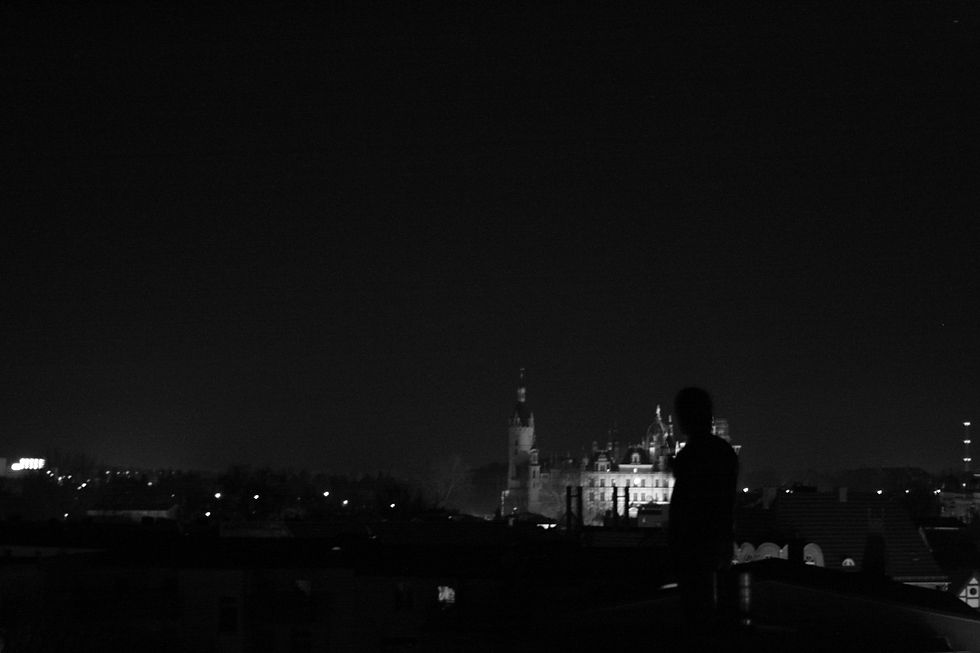 A person gazes at a nighttime cityscape.