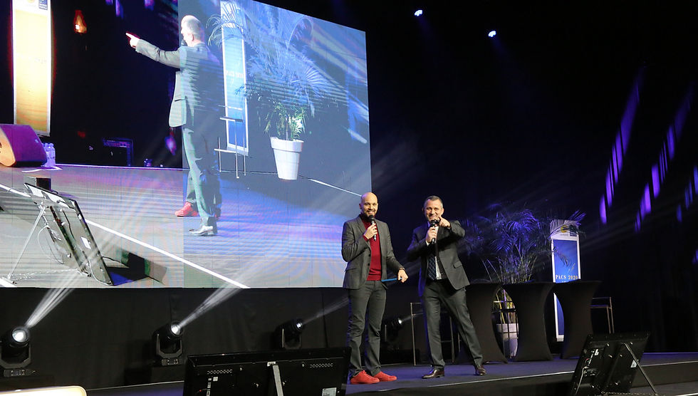 Moment de complicité entre Luc Terrier et un intervenant face au public lors d'un évènement professionnel