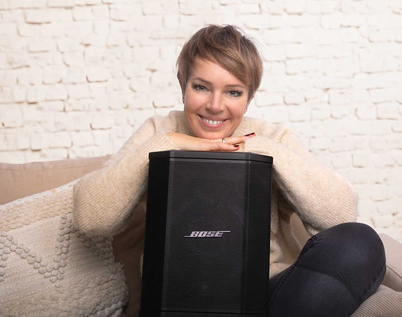 Die Sängerin Katja lächelt in die Kamera und stützt sich auf ihre Bose Box