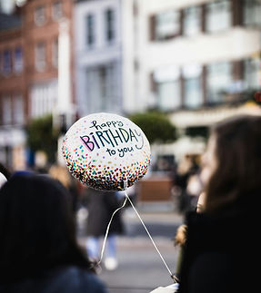 Happy Birthday Luftballon, Mädchen von hinten, Häuserfront im Hintergrund