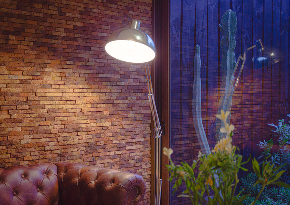 Ladrillo Listón Arcilla que aporta textura y calidez, acompañado de luz tenue y sofá de cuero elegante.