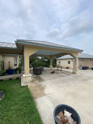 Renovated pavilion with columns wrapped in metal and covered with stone, replacing old rotten wood posts. 