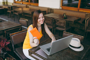 woman-outdoors-street-coffee-shop-cafe-sitting-table-working-modern-laptop-pc-computer-hol