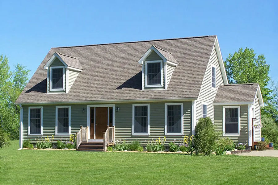 Classic Cape Cod custom modular home with light olive siding and a beautiful green lawn.
