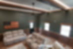 Wide view of the completed entertainment space featuring seating, custom wood wainscoting, windows, and finished flooring.