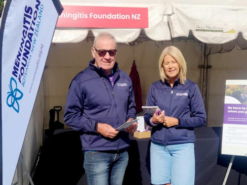 Man and lady outside a tent holding booklets