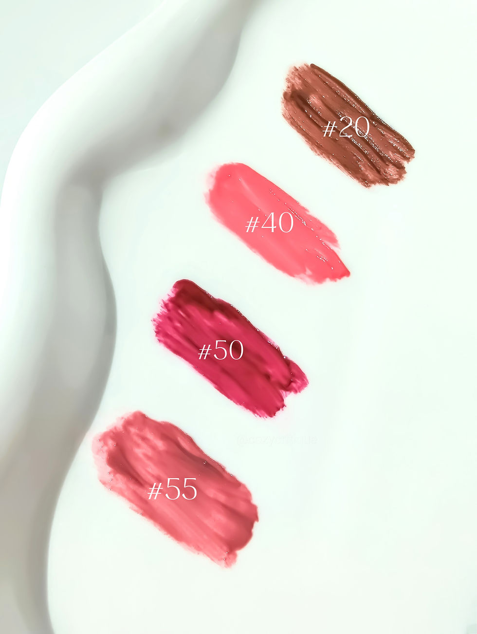 Four lipstick swatches on white background, labeled #20 (brown), #40 (pink), #50 (red), #55 (peach). Wavy edge detail.