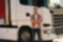 man smiling in front of semi truck cab