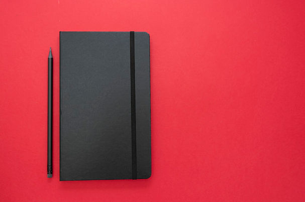 black-notebook-red-background-top-view-w