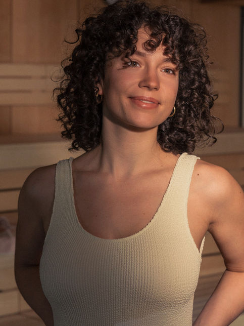 Frau mit Locken im Schwimmanzug in der Sauna