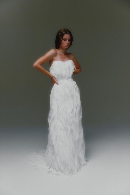 A gown that moves like a daydream—crafted from hundreds of hand-cut chiffon petals that flutter with every step. This poetic A-line silhouette is both soft and sculptural, featuring a strapless neckline and hidden internal corset for structure and support. Ethereal and weightless, it feels like wearing a breath of wind.
