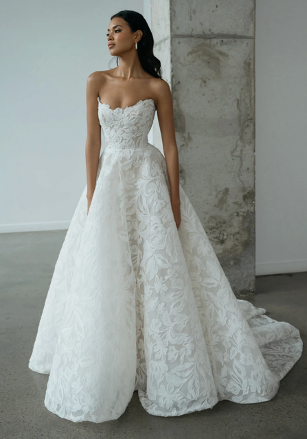 The intricate Iris cutwork tulle is laid onto a dramatic crinoline ball skirt that is left diaphanous and light as a feather, while the bodice is fully corseted for an impossibly flattering fit. The matching swags can be worn off the shoulder or detached for a striking transformation.