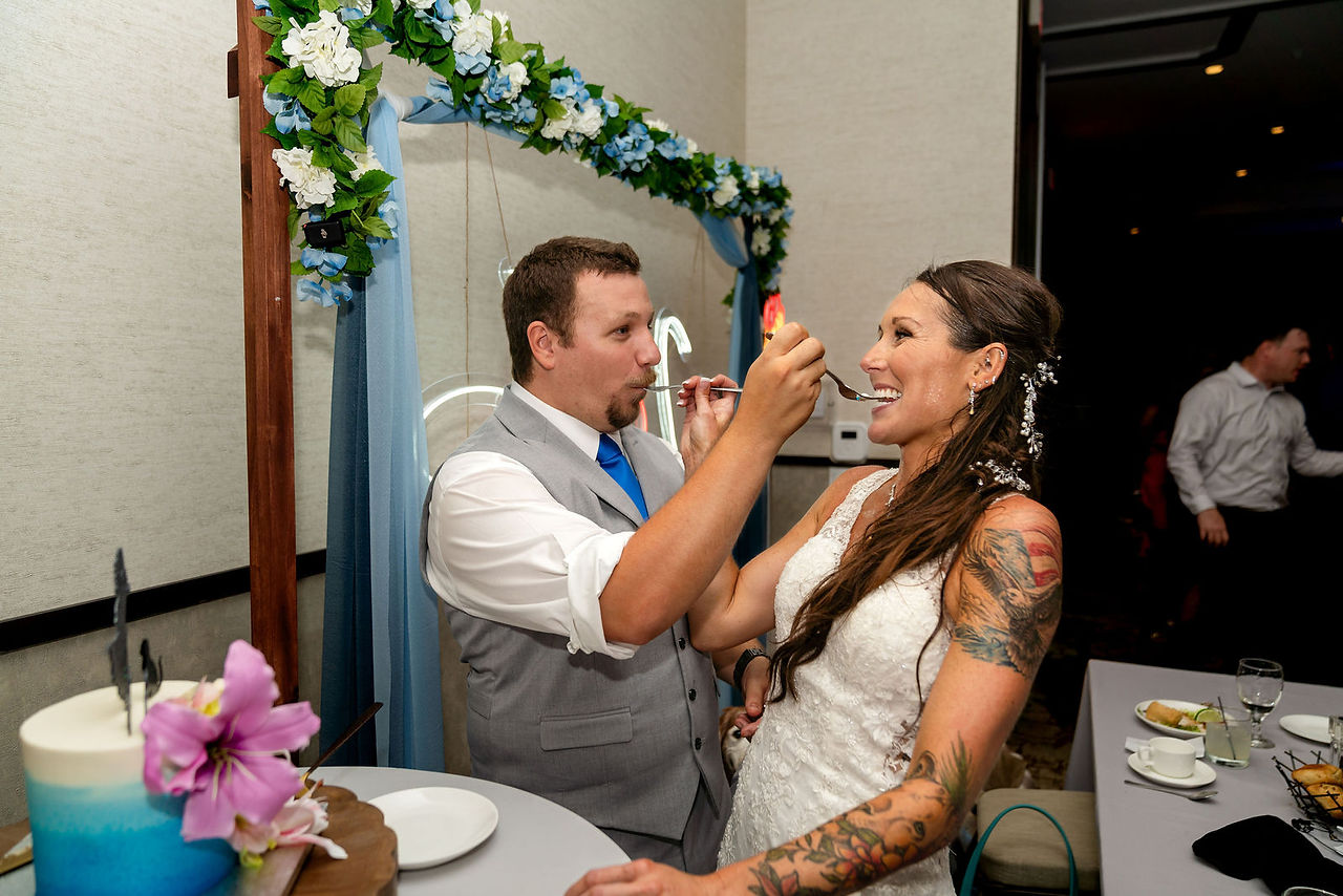 Bride and groom feeding each other first bite of the cake during cake cutting at their wedding at Hotel Melby in downtown Melbourne, Florida