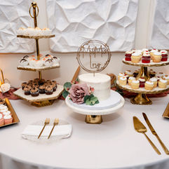 White wedding cake surrounded by desserts at a wedding at Harbour House in Indian Harbour Beach, Florida.