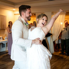 Bride throwing hand up in air in celebration as groom holds her waist during wedding at Harbour House in Florida. Photo by Pixel Groves